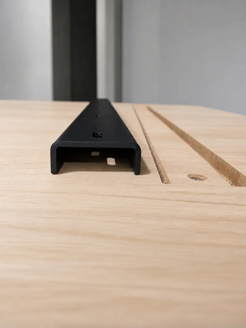 Black metal channel fitted into accurately machined grooves in a wood panel