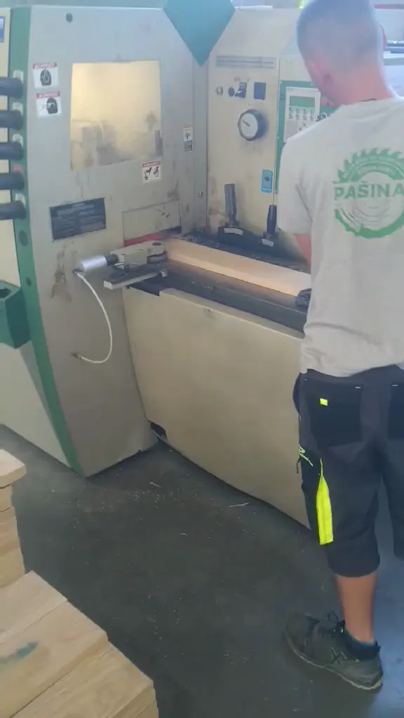 Radnik za blanjalicom sa složenim blanjanim bukovim elementima ispred